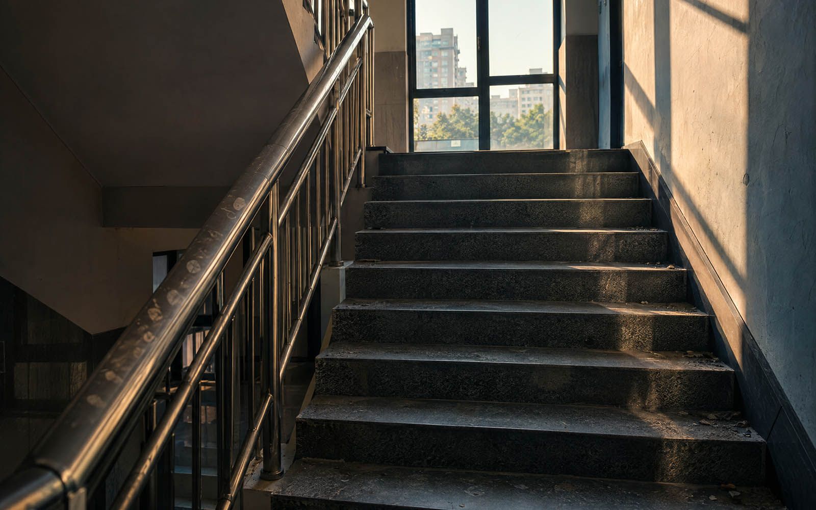 Treppenhaus mit stumpfen Stufen, Staub in den Ecken und Fingerspuren am Handlauf